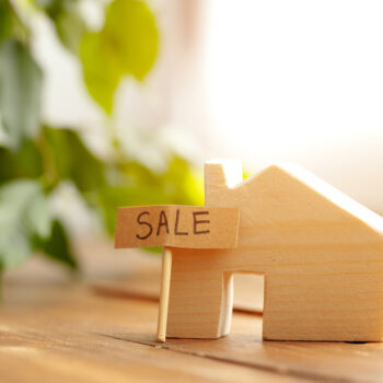 wooden-house-model-and-for-sale-sign-2021-09-03-13-06-40-utc